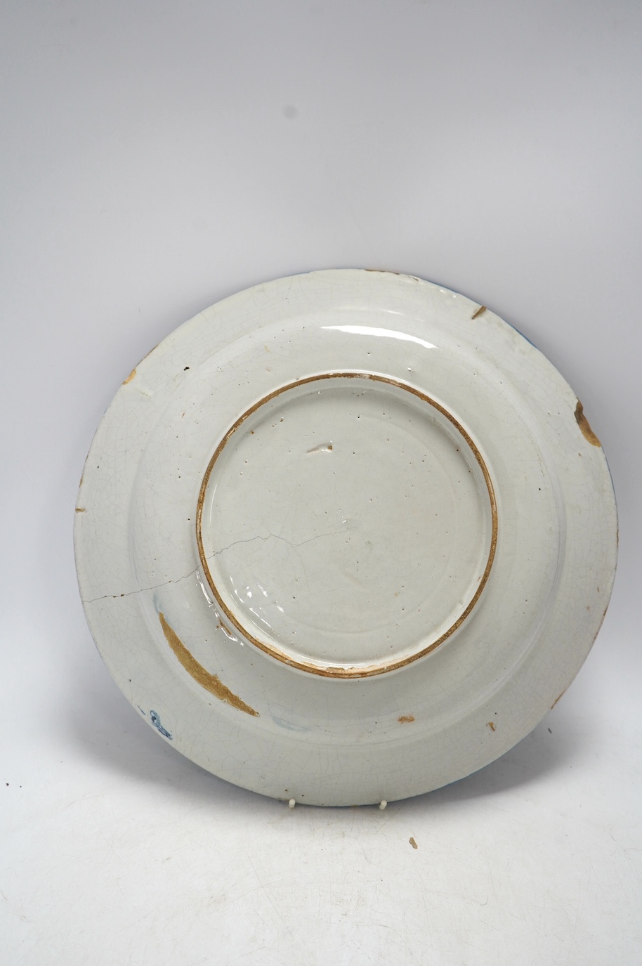 An 18th century Dutch Delft blue and white charger, diameter 33.5cm. Condition - poor, large crack running across half the diameter of the plate and through to the base, as well as some chips to the rim including one lar